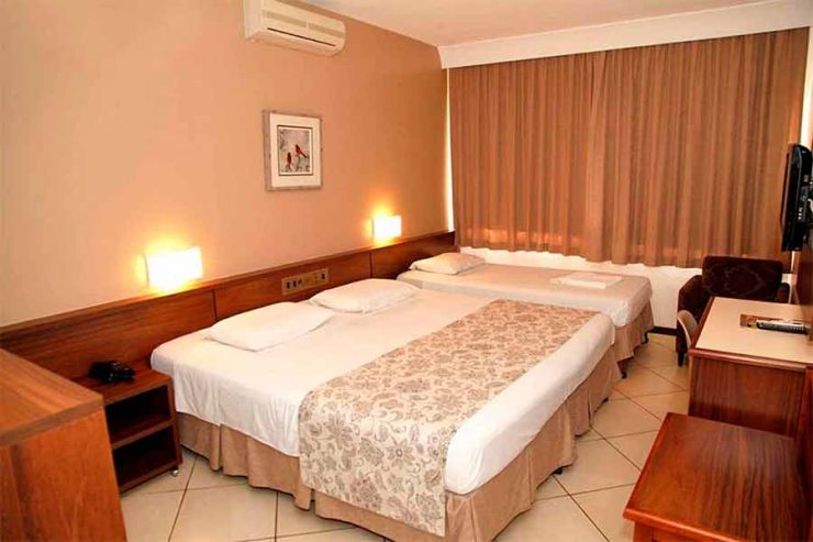 Quarto do San Rafael, em Foz do Iguaçu, com duas camas, cortinas fechadas e ar-condicionado