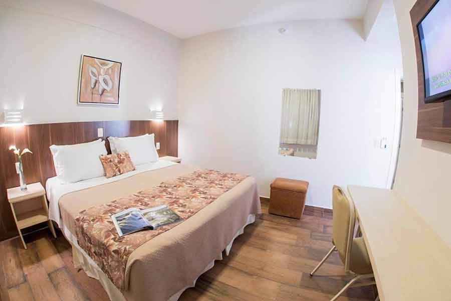 Quarto do Tarobá Hotel com cama de casal , TV e mesa