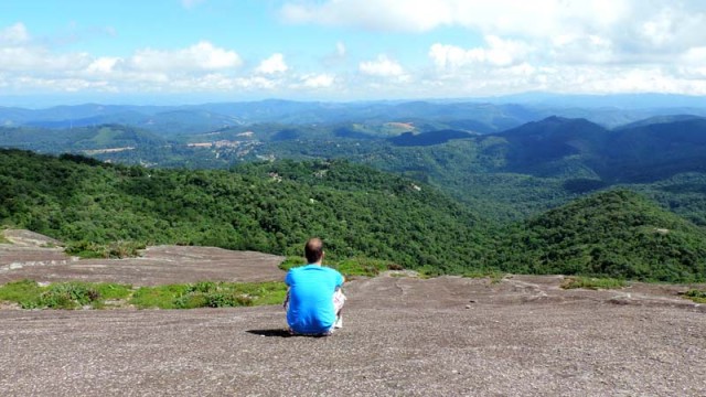 Homem sentado no alto da Pedra Redonda em Monte Verde, Minas Gerais