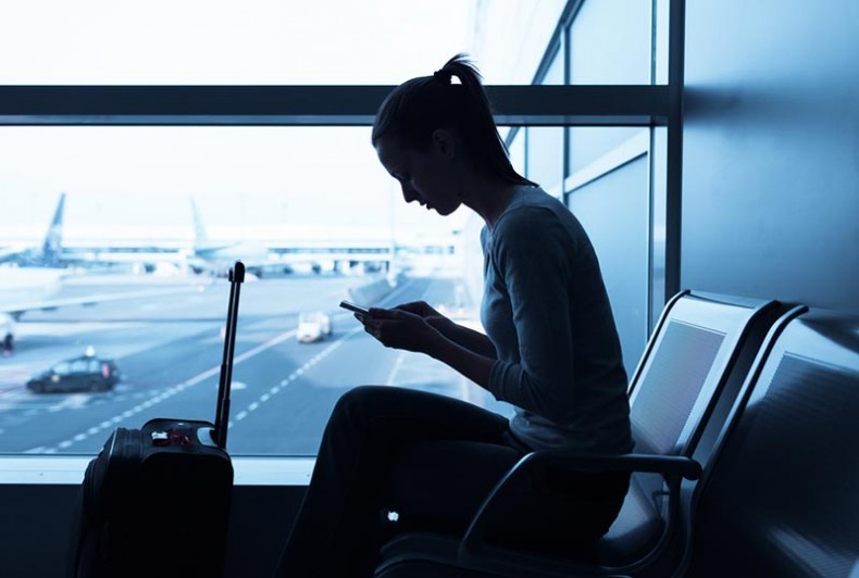 Mulher Aguardando Voo Sentada no Aeroporto e com Seguro Viagem Internacional Contratado