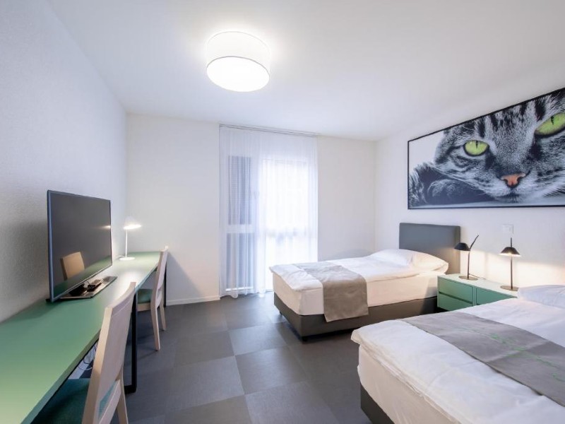 Quarto do The Freddie Mercury Hotel, dica de onde ficar em Montreux, com duas camas de solteiro e decoração clara