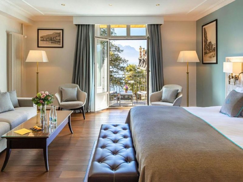 Quarto do Grand Hotel Suisse Majestic com cama de casal, sofá e poltronas