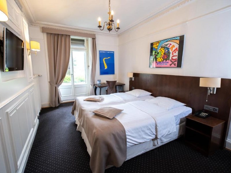 Quarto do Hotel Helvetie, dica de onde ficar em Montreux, com duas camas de solteiro e cabeceira de madeira