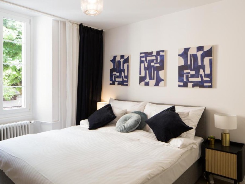 Quarto da Marché 28 Guesthouse com cama de casal com almofadas e decoração em branco e preto