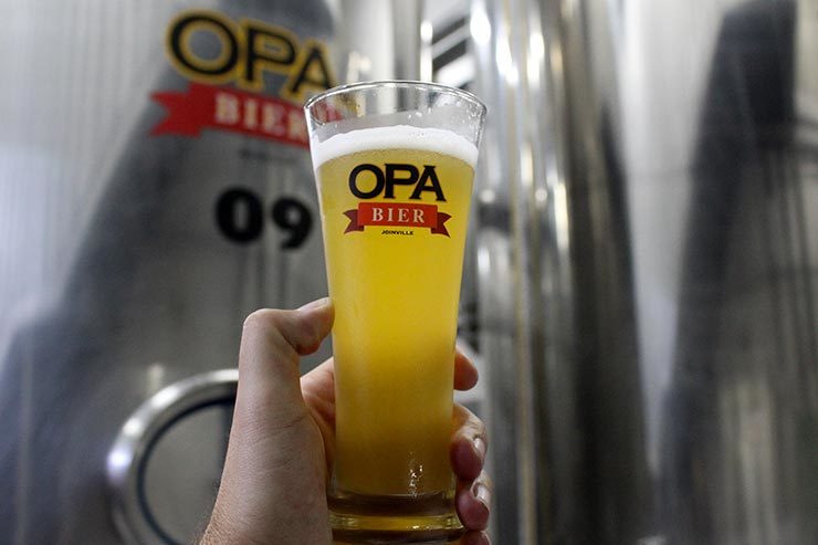 Mão segura copo de cerveja da Opa Bier (Foto: Esse Mundo É Nosso)