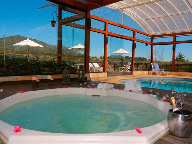 Banheira de hidromassagem coberta em dia de céu azul no Esquilo Hotel, dica de onde ficar em Monte Verde