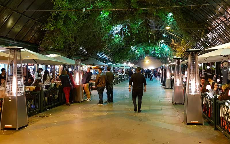 Pessoas andando e sentadas em restaurante na Rua Coberta, mais uma dica de o que fazer em Gramado e Canela