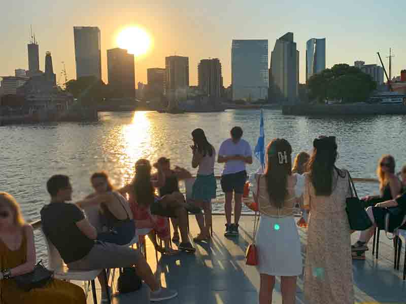 Pessoas contemplam o pôr do sol em passeio de barco pelo Rio de la Plata, dica do que fazer em Buenos Aires