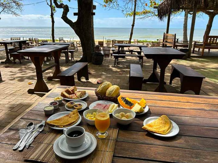 Café da manhã da Coco Brasil, uma das pousadas em Caraíva, com ovos mexidos e crepioca e vista para o mar