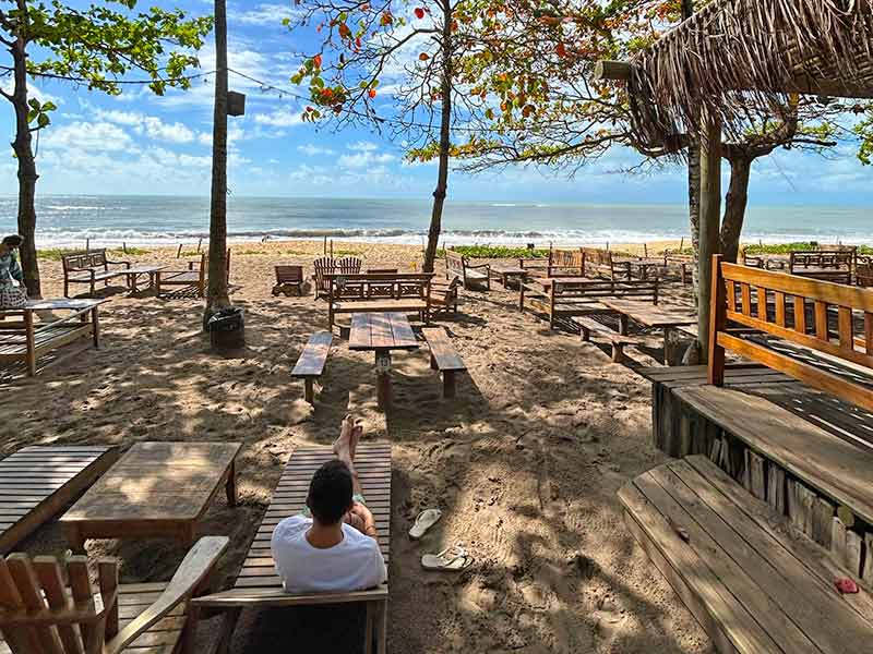 Homem deitado em cadeira aproveita a praia de Caraíva na pousada Coco Brasil