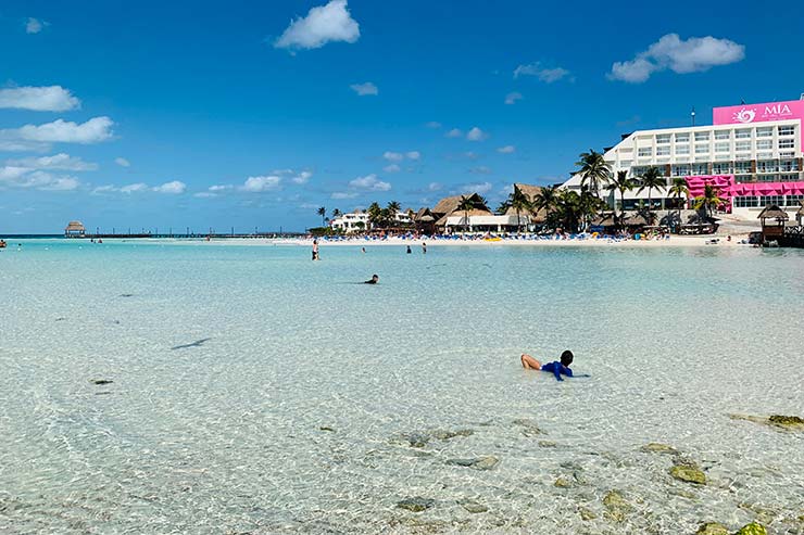 Criança se diverte no mar calmo, transparente e raso da Playa Norte