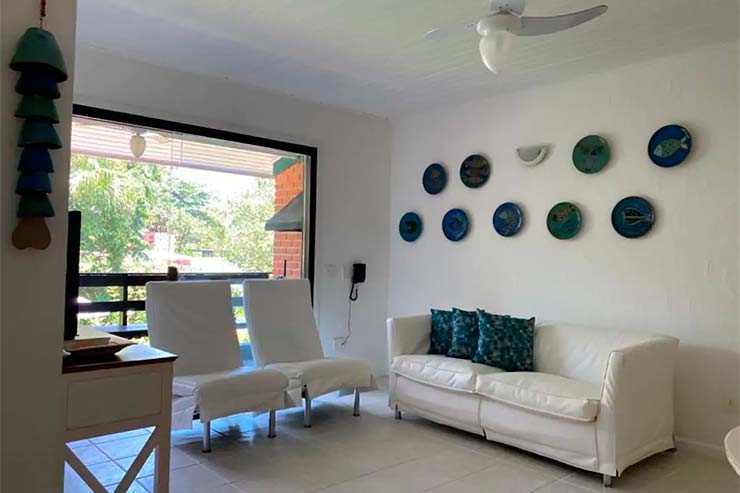 Sala de estar com poltronas, sofá e janelas da Brisas do Mar (Foto: Divulgação)