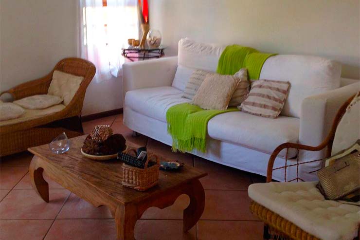 Sala de estar com sofá, mesa de centro e poltrona de casa em Juquehy (Foto: Divulgação)