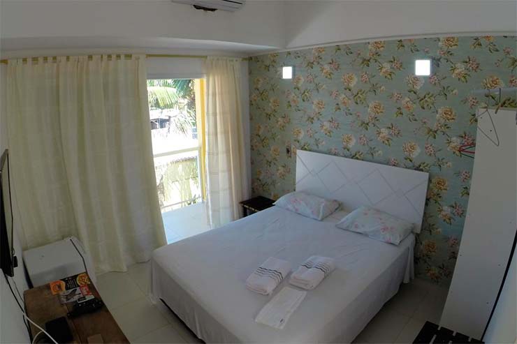 Onde ficar em Juquehy: Quarto com cama, janela e guarda-roupa do Ipê Suítes (Foto: Divulgação)