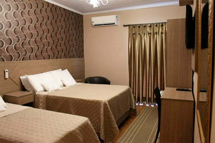 Pousada em Ilha Grande: Quarto da Beto's Pousada com duas camas, TV e roupa de cama em tom marrom (Foto: Divulgação)