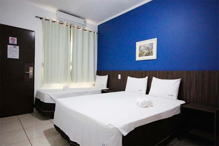 Acomodação da JS Thermas com cama de casal e cama de solteiro com parede azul (Foto: Divulgação)