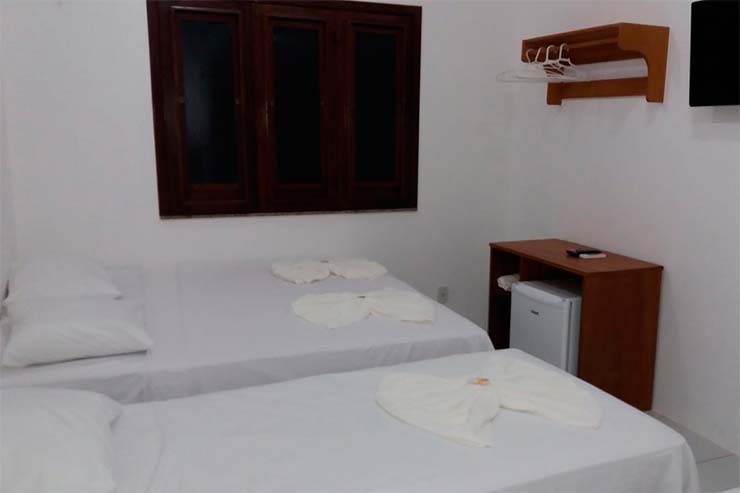 Quarto simples com duas camas e frigobar da pousada Vilas Boas (Foto: Divulgação)