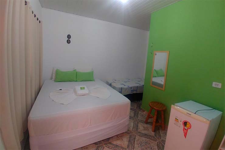Pousadas em Alter do Chão, no Pará:  Quarto da Coração Verde com cama, espelho, frigobar e parede verde (Foto: Divulgação)
