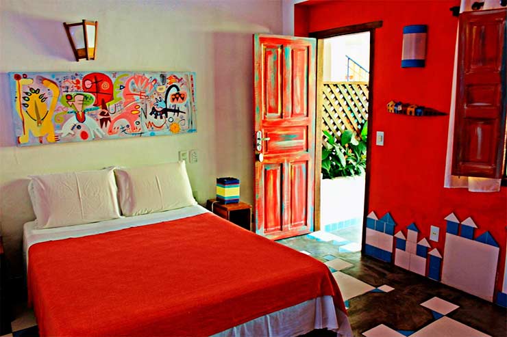Pousada em Arraial d'Ajuda: Quarto com cama de casal e decoração em vermelho da Art Hotel Aos Sinos dos Anjos (Foto: Divulgação)