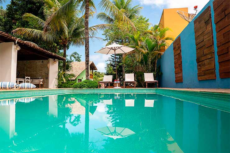 Piscina da Calypso Inn com cadeiras e guarda-sol (Foto: Divulgação)