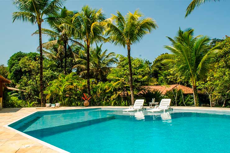 Pousadas em Trancoso: Piscina da Jacarandá com árvores e espreguiçadeiras (Foto: Divulgação)