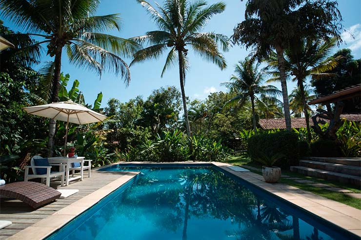 Piscina com mesa e guarda-sol ao lado na Jardim das Margaridas (Foto: Divulgação)