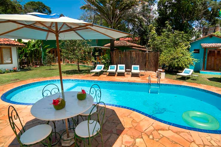 Piscina com espreguiçadeiras e mesa com guarda-sol da Raízes do Brasil (Foto: Divulgação)