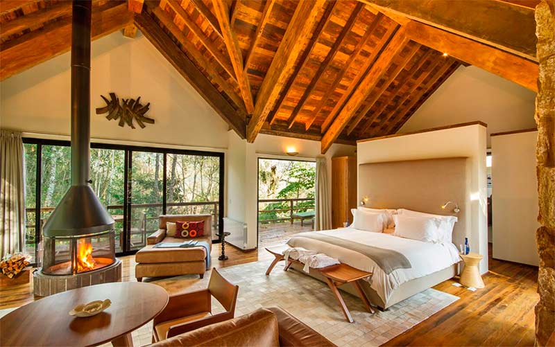 Quarto espaçoso com cama de casal, lareira e mesa da Six Senses Botanique (Foto: Divulgação)