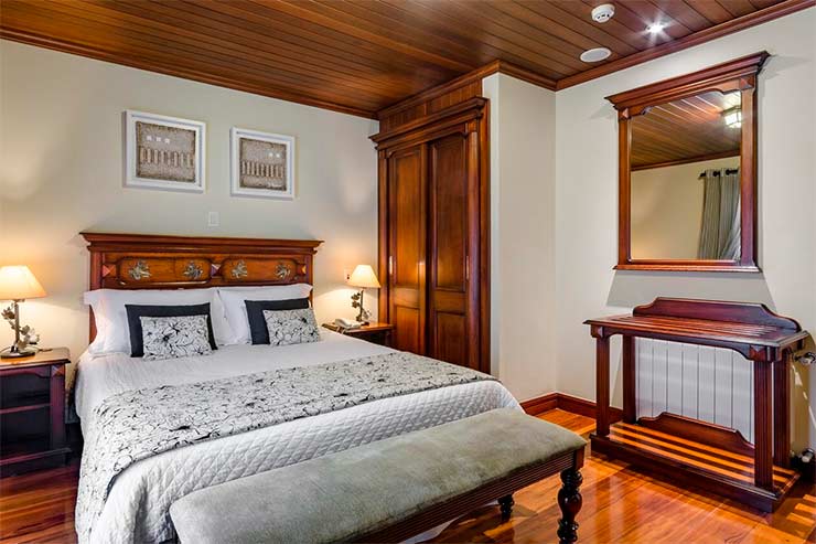 Quarto com cama de casal com móveis de madeira da Pousada Villa D'Biagy (Foto: Divulgação)