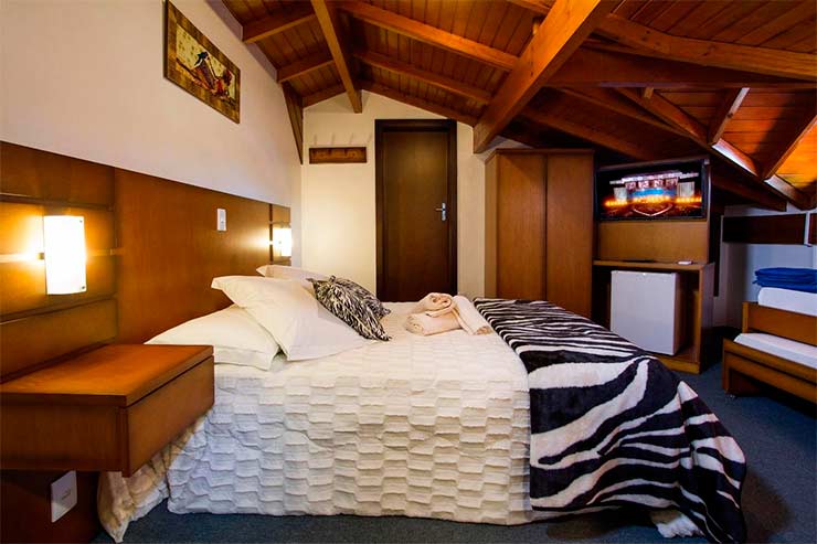 Onde ficar em Canela: Quarto da Pousada Hencke Haus com cama de casal, frigobar e móveis de madeira (Foto: Divulgação)