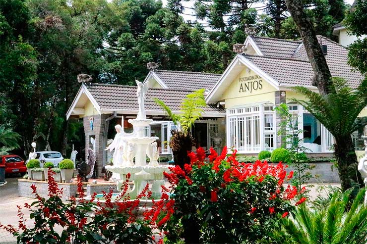 Parte externa da Pousada dos Anjos com fonte e jardim com flores (Foto: Divulgação)