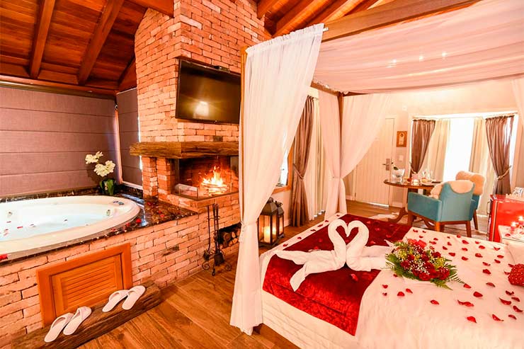 Onde ficar em Gramado: Quarto da Cabanas do Tio Müller com cama de casal, poltrona e banheira (Foto: Divulgação)