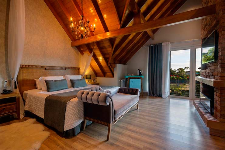 Quarto espaçoso do Valle Dincanto com cama de casal e frigobar (Foto: Divulgação)