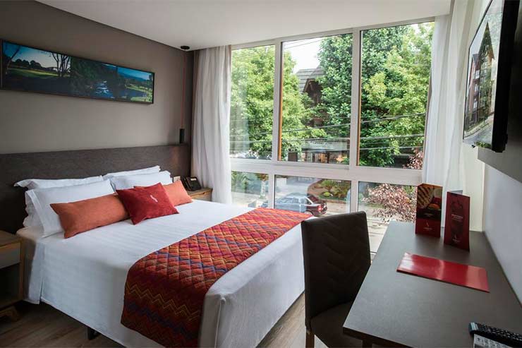 Onde ficar em Gramado: Quarto com grande janela, cama de casal e TV do Laghetto Stilo Centro (Foto: Divulgação)