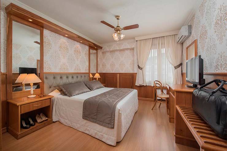 Onde ficar em Gramado: Quarto espaçoso com cama de casal e TV em decoração de madeira do Serrazul (Foto: Divulgação)