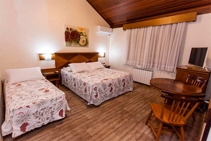 Quarto simples do Tri Hotel Lago Gramado com duas camas, TV e mesa (Foto: Divulgação)