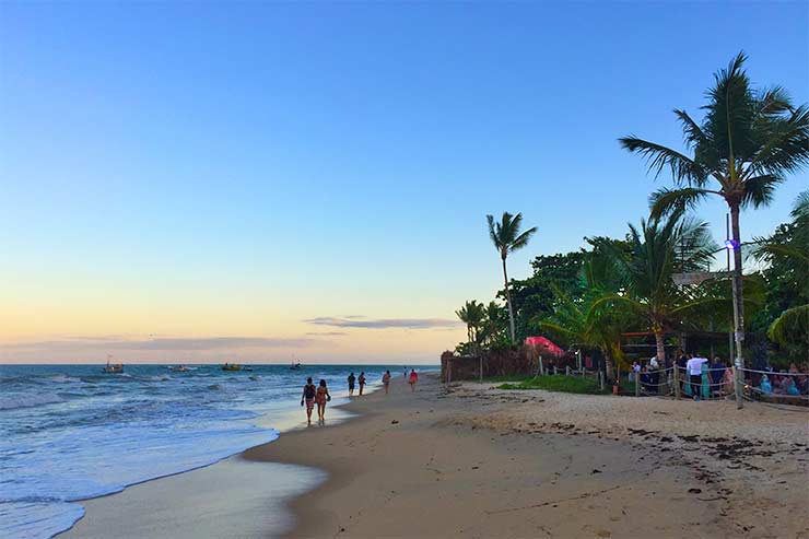 Final do dia na Praia dos Nativos com céu em tons azuis e amarelados