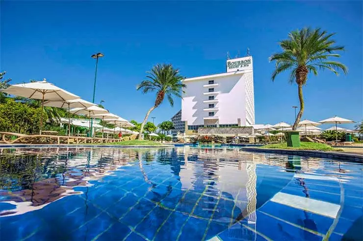 Melhor Resort do Brasil: Piscina do Bourbon Atibaia com prédio ao fundo e algumas árvores em dia de céu azul