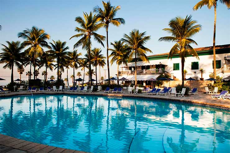 Área da piscina do Casa Grande Hotel com árvores e espreguiçadeiras em dia de céu azul