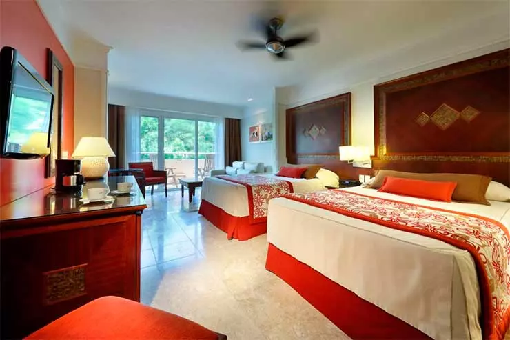 Quarto do Grand Palladium Imbassaí com duas camas de casal, TV e tons marrons e vermelhos (Foto: Divulgação)