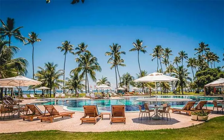 Grande piscina do Patachocas com espreguiçadeiras e coqueiros em dia de sol