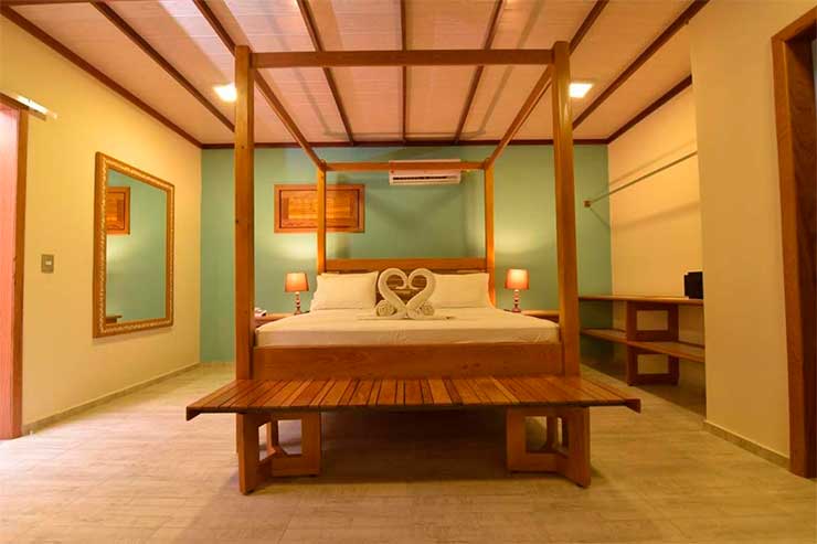 Acomodação do Porto Preguiças, no Maranhão, com cama de casal, espelho, abajur e parede esverdeada