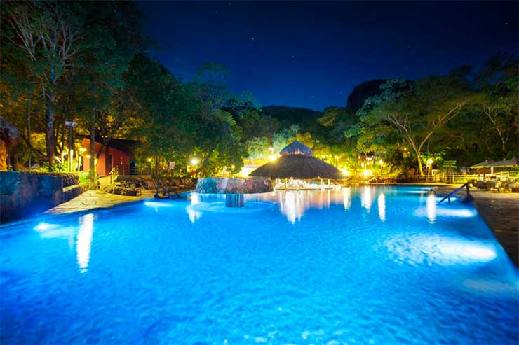 Piscina do Hotel Pousada, do Rio Quente Resorts, com árvores e luzes à noite