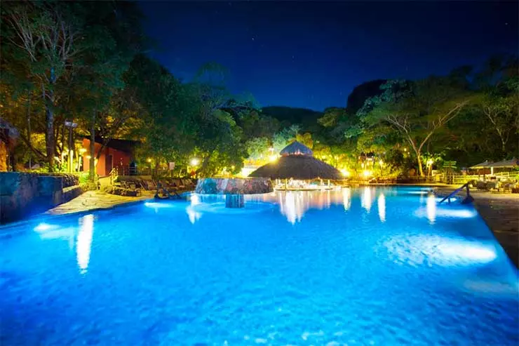Piscina do Hotel Pousada, do Rio Quente Resorts, com árvores e luzes à noite