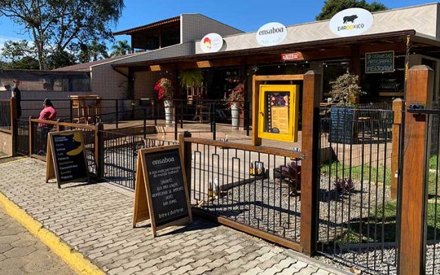 Entrada do Bar do Xico com cardápio na porta e outros estabelecimentos ao lado