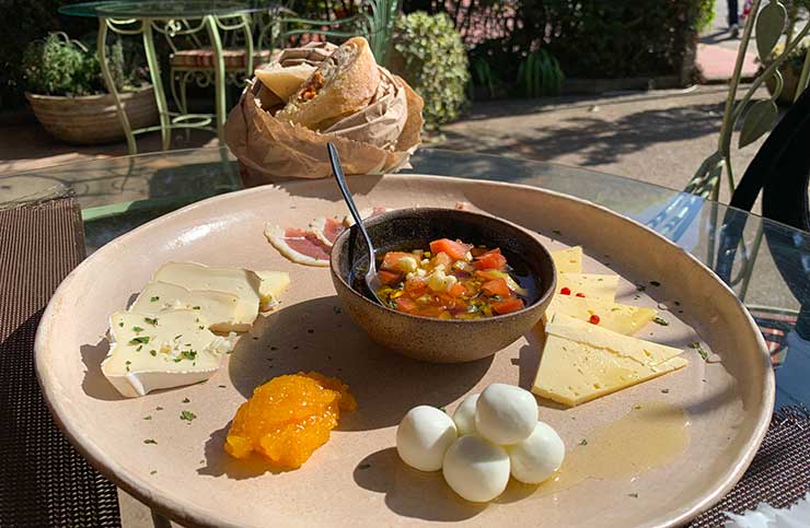 Entrada dos Bistrô das Meninas com com pães artesanais, queijo Alagoa, Boursin, tomatinho no azeite, camembert, geleia de damasco e fatias de pato curado