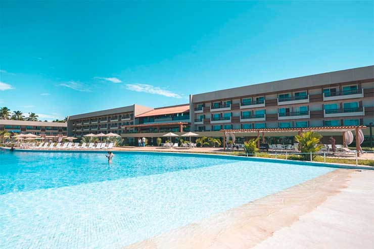 Grande piscina do Japaratinga, resort em Alagoas, com acomodações ao fundo em dia de céu azul