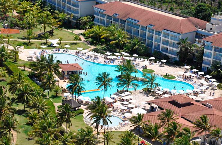 Vista aérea do Sauípe Resorts com piscina, espreguiçadeiras e árvores em dia de sol
