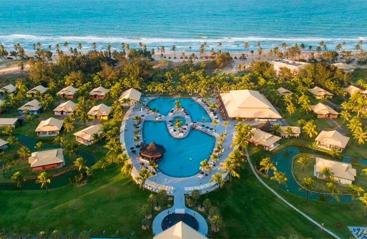 Vista aérea do Vila Galé Cumbuco com piscinas e acomodações em meio a jardins e em frente à praia