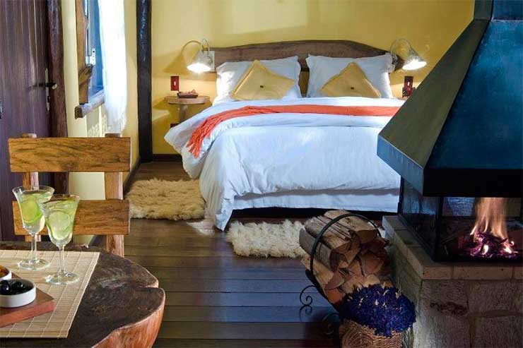Pousada em Visconde de Mauá: Quarto da Pousada dos Amores com cama de casa, lareira e mesa com taças